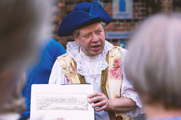 Stadtführung mit Guide verkleidet als Kommissar Bergengrün; er zeigt den Teilnehmenden ein Bild. 